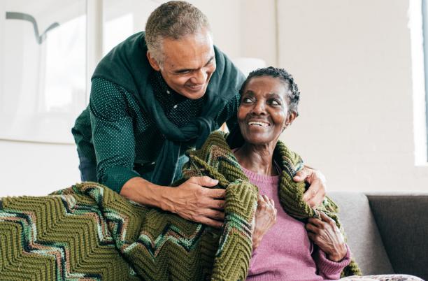 A man puts a blanket over his mother's shoulders