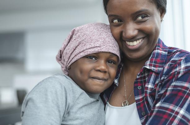 A mother hugs her daughter who is wearing a bandana
