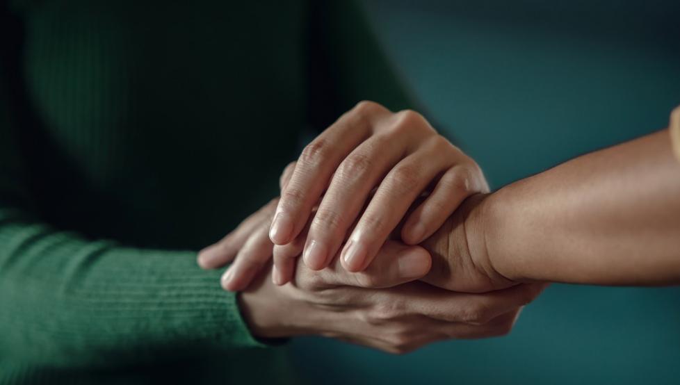 Stock photo of two people holding hands supportively