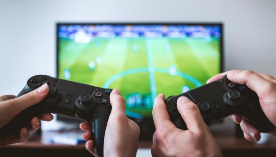 A stock photo of two people gaming on a large screen TV