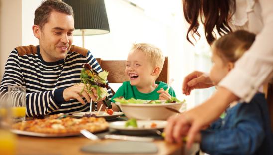 A stock photo of a young child enjoying a family meal with their father