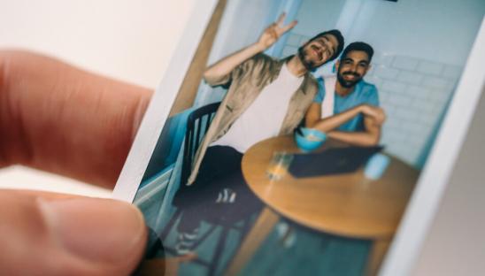 Person holding a polaroid of two people smiling