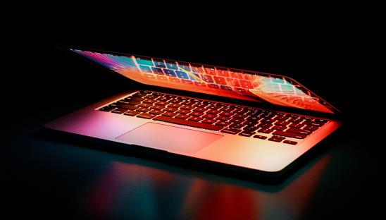 A stock photo of a laptop computer half-opened in low light